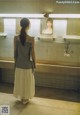 A woman standing in front of a mirror in a bathroom.