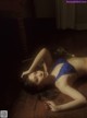 A woman laying on the floor in a blue lingerie.