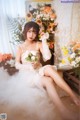 A woman in a wedding dress sitting on the floor with flowers.