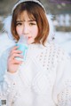 A woman in a white sweater holding a bottle of water.