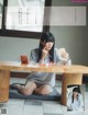 A woman sitting at a table with a mirror in her hand.