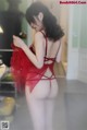 A woman in a red lingerie is posing for the camera.