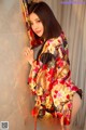 A woman in a kimono leaning against a wall.