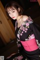 A woman in a black and pink kimono posing for a picture.