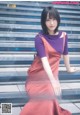 A woman in a red dress sitting on some steps.