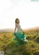 A woman in a long green skirt standing in a field.